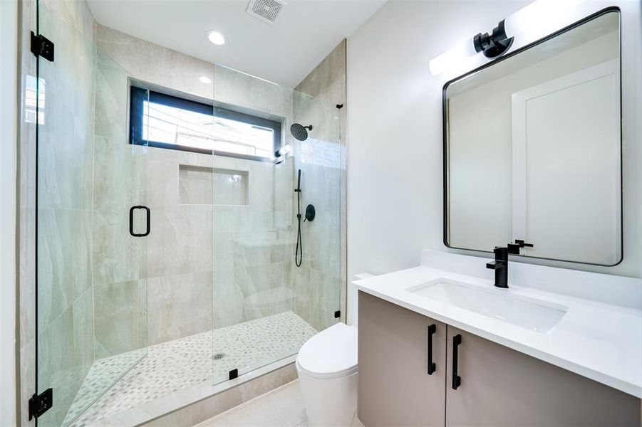 Bathroom with vanity, tile patterned flooring, toilet, and a shower with door