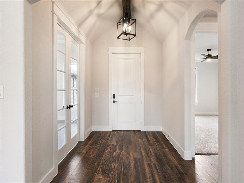 Entrance foyer featuring ceiling fan with notable chandelier, lofted ceiling, and dark wood-type flooring