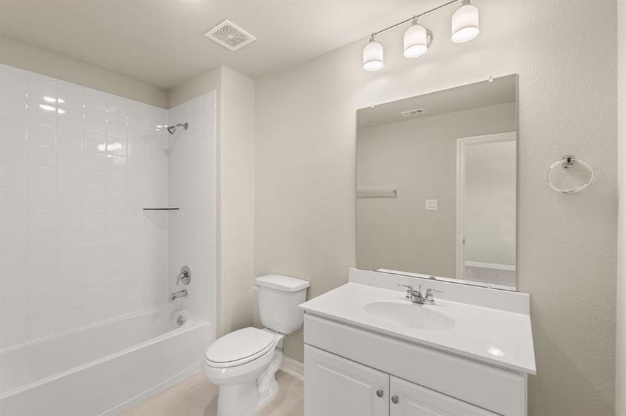 The secondary bath features tile flooring, white cabinetry and light countertops and a shower/tub combo. Perfect for accommodating any visiting family and friends.