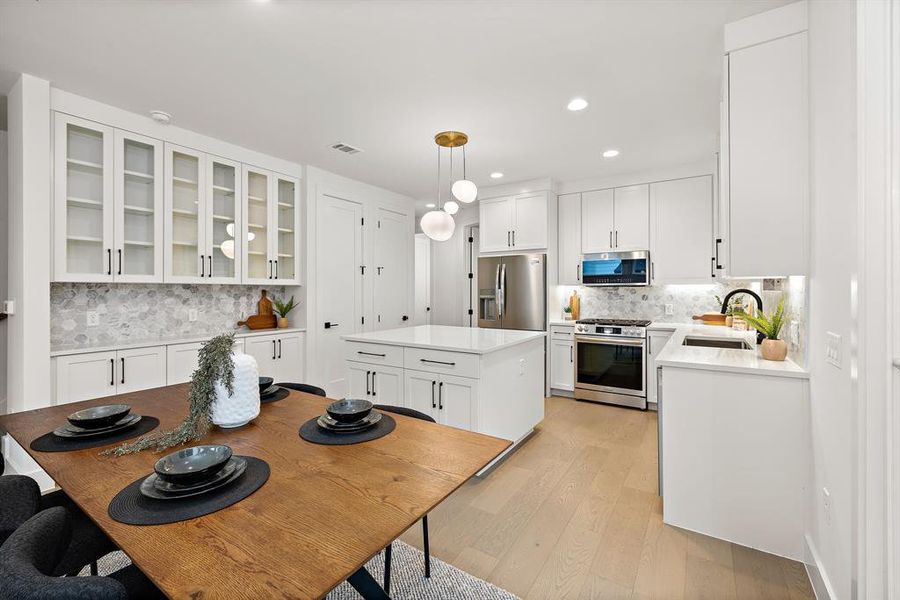 Beautiful kitchen has custom cabinetry with soft-close drawers and doors, row of glass front cabinets, custom hex tile backsplash, Quartz countertops, two pantries, gas range.