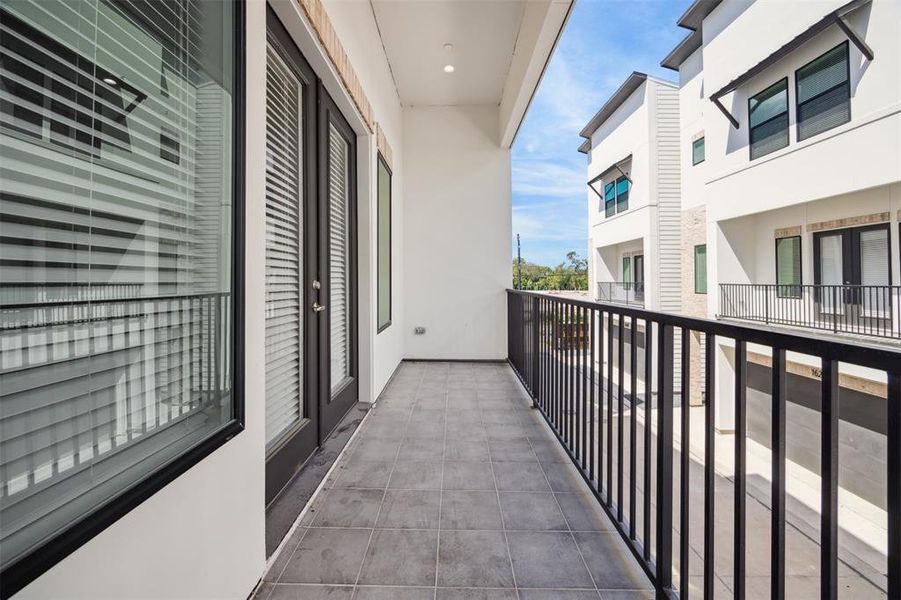 The living and dining spaces on the second floor have French doors that lead out to this spacious covered balcony.