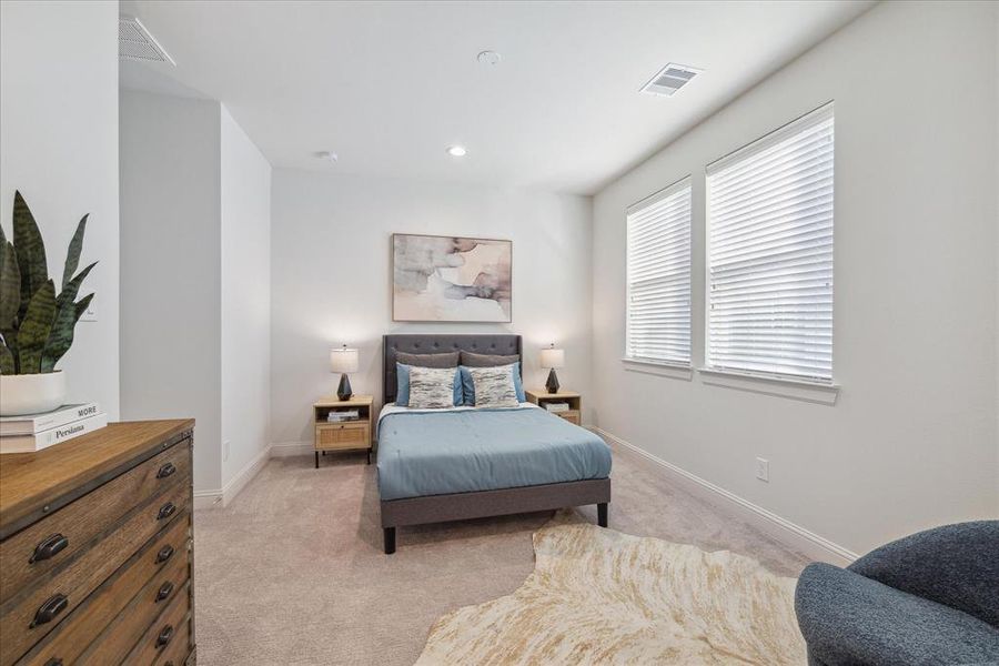 This third-floor secondary bedroom offers a spacious layout with ample natural light flowing through large windows. Neutral tones and soft carpeting create a cozy atmosphere, perfect for relaxation.