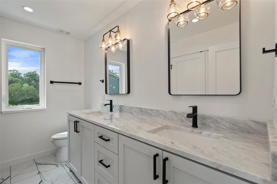 Bathroom with a notable chandelier, tile patterned floors, toilet, and dual bowl vanity