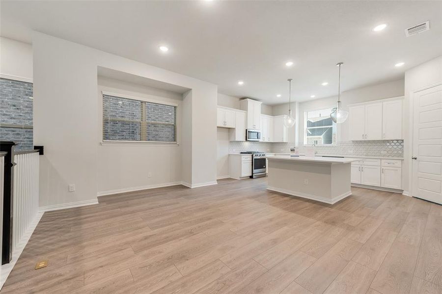 Kitchen featuring light hardwood / wood-style flooring, white cabinetry, appliances with stainless steel finishes, and a center island