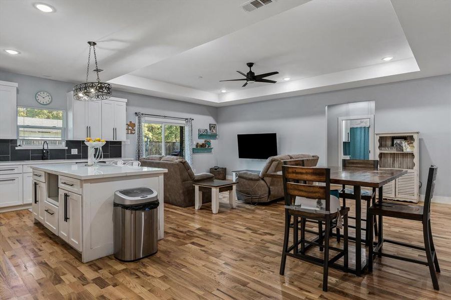 Kitchen featuring a center island, white cabinetry, hardwood, and decorative light fixtures