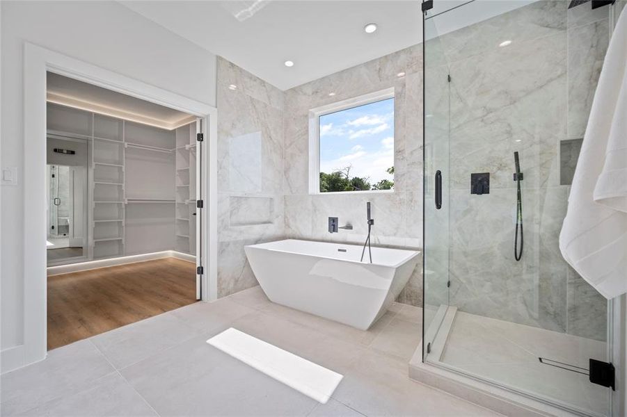 Bathroom featuring shower with separate bathtub, tile patterned flooring, and tile walls