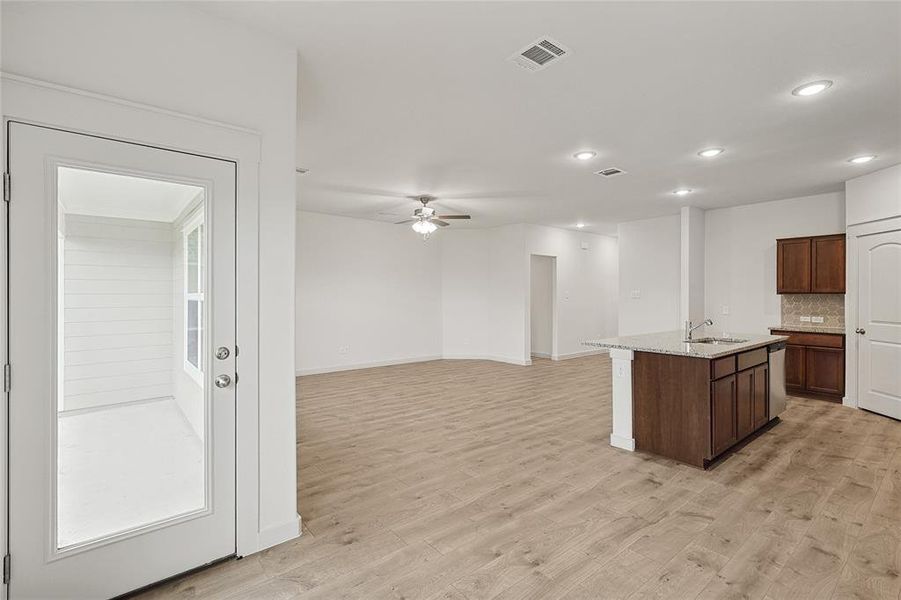 Kitchen featuring light hardwood / wood-style flooring, ceiling fan, backsplash, and an island with sink