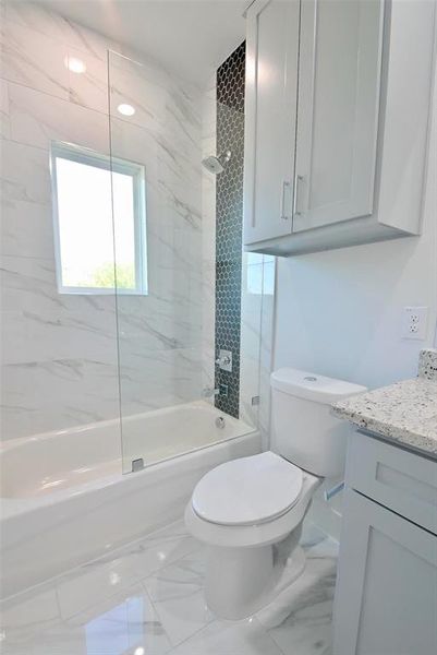 Full bathroom with tiled shower / bath combo, vanity, and toilet