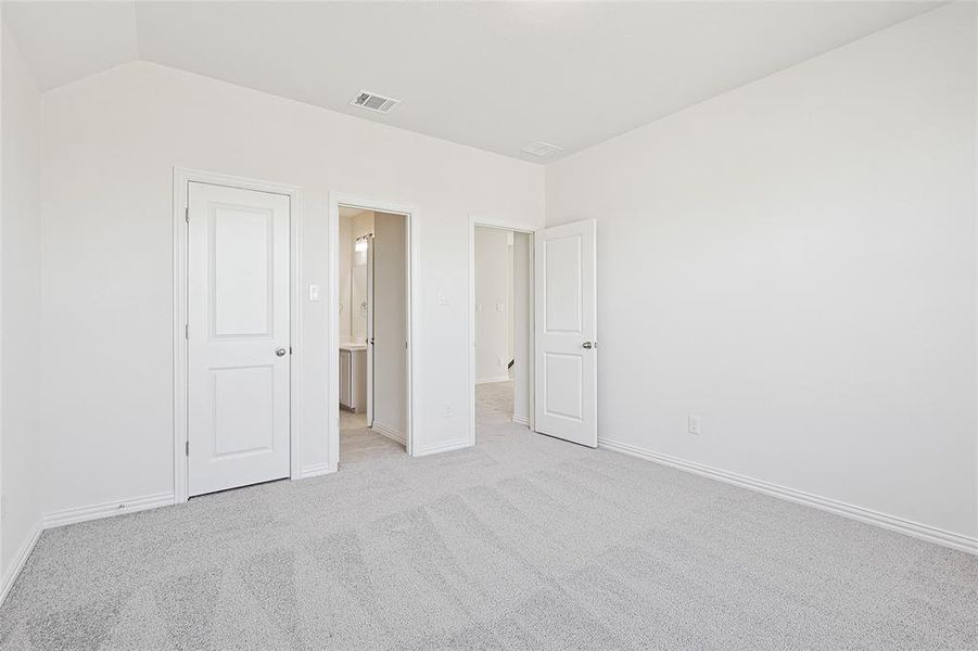 Unfurnished bedroom featuring lofted ceiling and light colored carpet