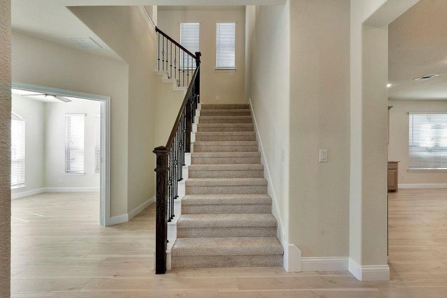 Stairway featuring a wealth of natural light, ceiling fan, and light wood-type flooring