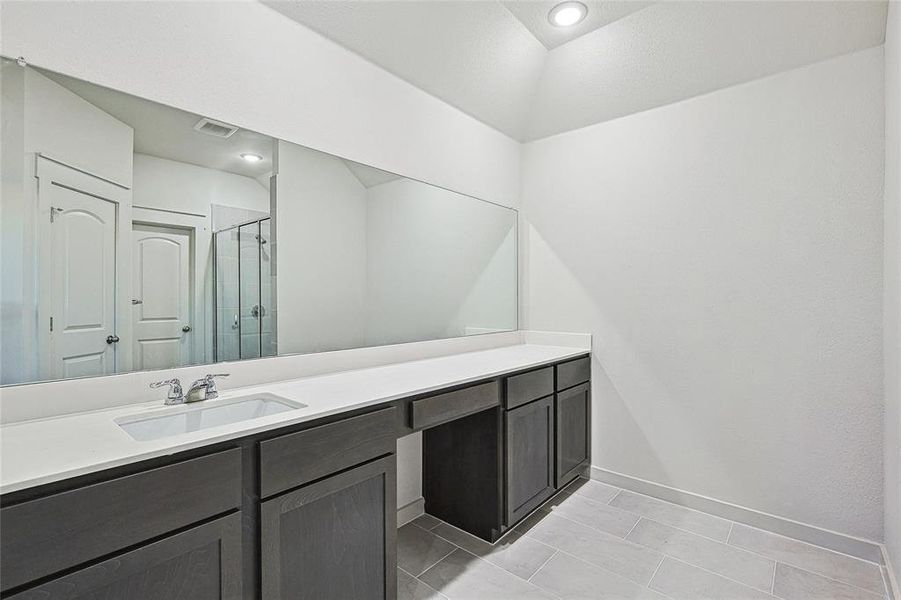 Bathroom with tile patterned flooring, a shower with door, and vanity