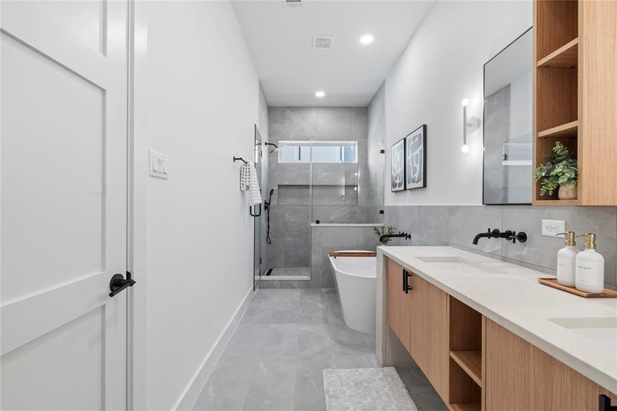 This bathroom combines contemporary elements with a calming ambiance, highlighted by the freestanding tub, double sinks, and spacious shower. Minimalist black fixtures and open shelving add a modern touch, making it a beautifully functional retreat.