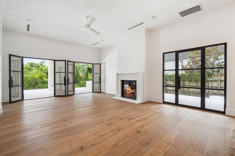 The family room is centered around a custom fluted cast stone fireplace, creating a warm and inviting atmosphere. Two sets of French Durango doors open to the covered patio and summer kitchen, offering seamless indoor-outdoor entertaining.