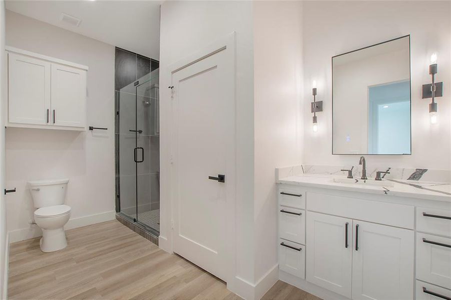 Bathroom featuring an enclosed shower, wood-type flooring, vanity, and toilet