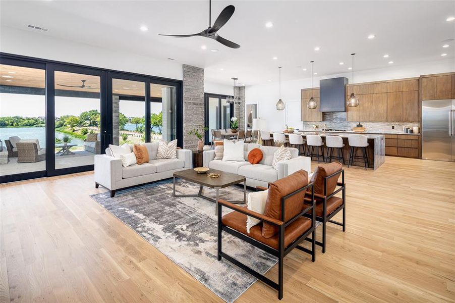 Living room featuring ceiling fan with notable chandelier and light hardwood / wood-style floors