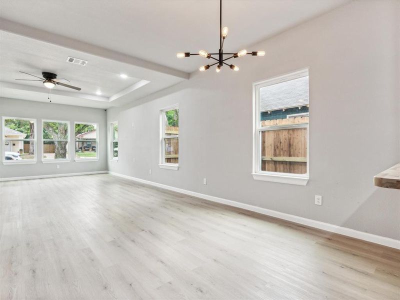 Unfurnished living room featuring ceiling fan with notable chandelier and light hardwood / wood-style flooring