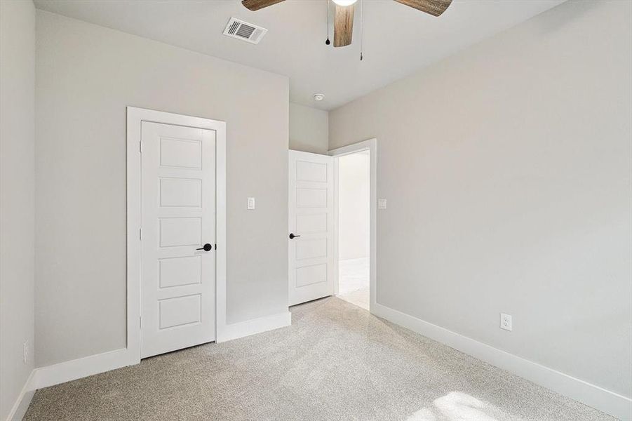Unfurnished bedroom with ceiling fan and light carpet