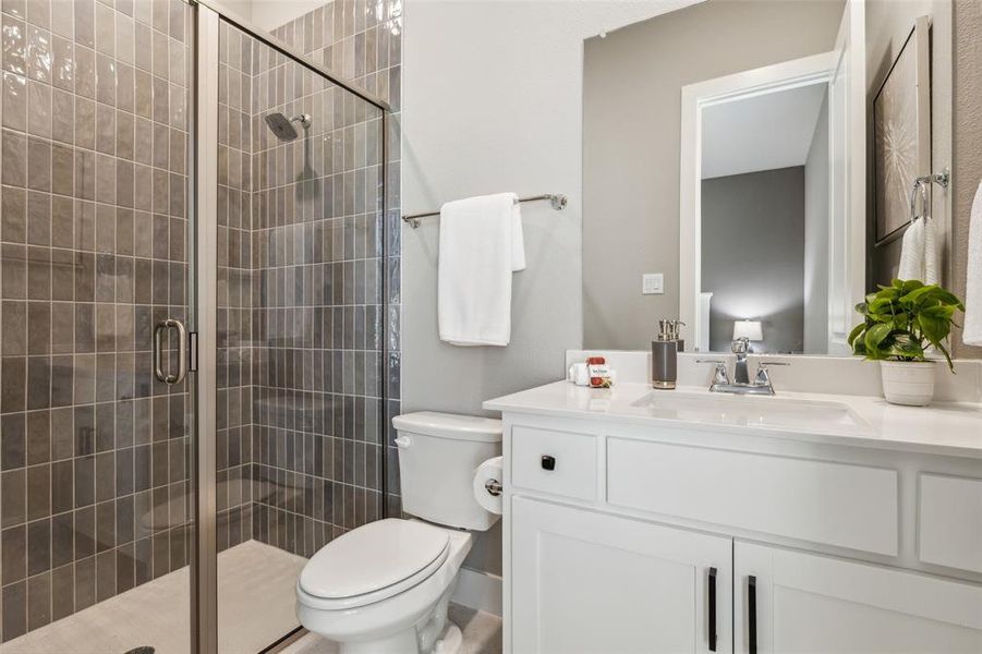 Bathroom featuring toilet, vanity, and a shower with door