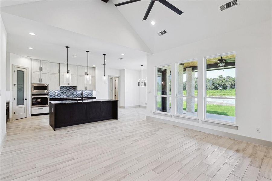 Kitchen with a center island with sink, ceiling fan, stainless steel appliances, and white cabinetry