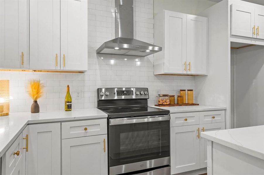 Kitchen featuring decorative backsplash, wall chimney range hood, light stone countertops, white cabinets, and electric stove