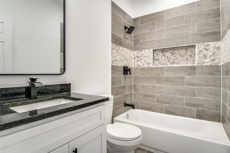 Full bathroom featuring vanity, tiled shower / bath combo, and toilet