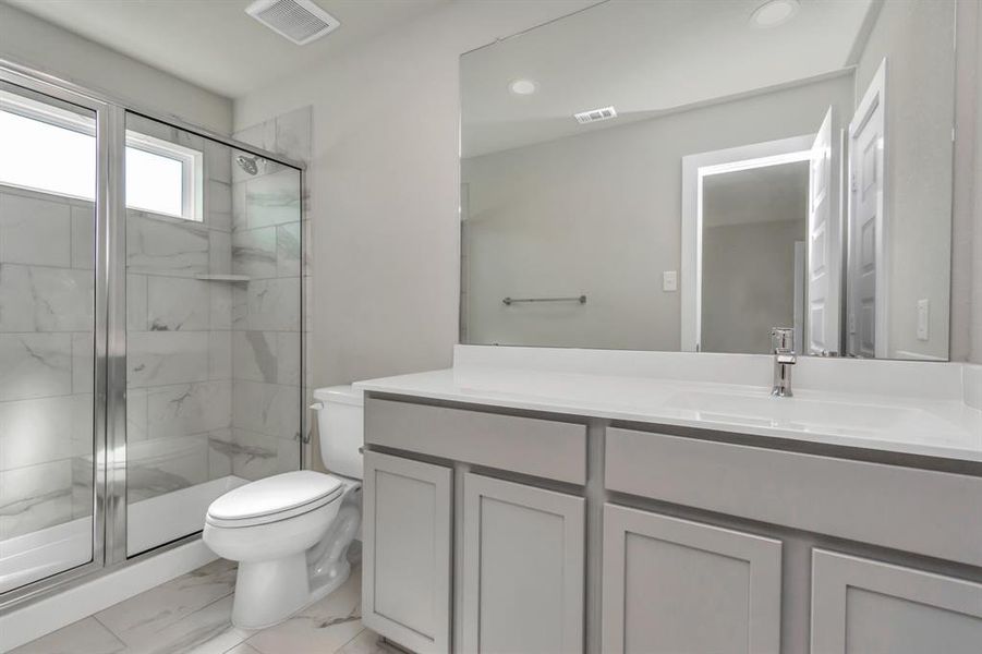 Experience sophistication in the secondary bathroom, where tile flooring complements a walk-in shower with tile surround. Sample photo of completed home with similar floor plan. As built color and selections may vary.