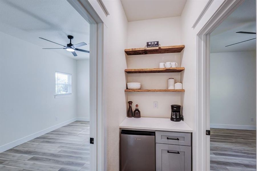 Bar featuring ceiling fan, stainless steel refrigerator, and light wood-type flooring