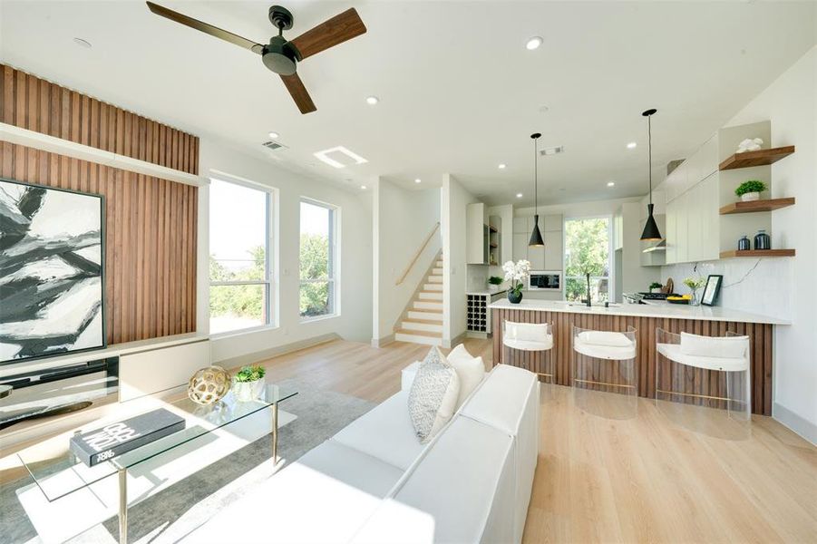 Living room with ceiling fan, sink, and light wood-type flooring