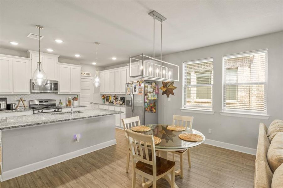 Kitchen featuring white cabinets, decorative backsplash, light stone counters, and stainless steel appliances