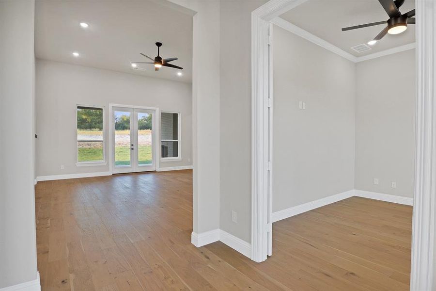 Empty room featuring french doors, ornamental molding, light hardwood / wood-style floors, and ceiling fan