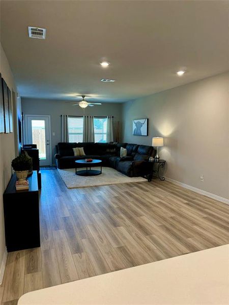 Living room with ceiling fan, hardwood / wood-style flooring, and a healthy amount of sunlight