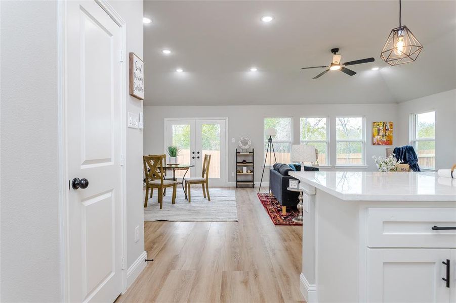 Kitchen with lofted ceiling, white cabinets, ceiling fan, light hardwood / wood-style flooring, and pendant lighting