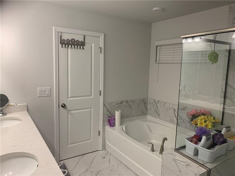 Bathroom featuring tile floors, a bathtub, and double vanity