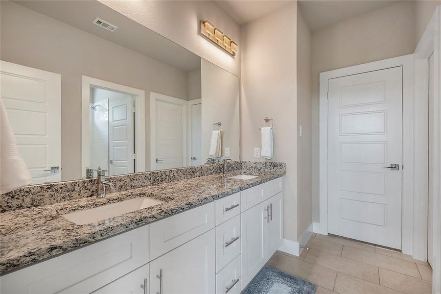 Bathroom featuring vanity with extensive cabinet space, double sink, and tile floors