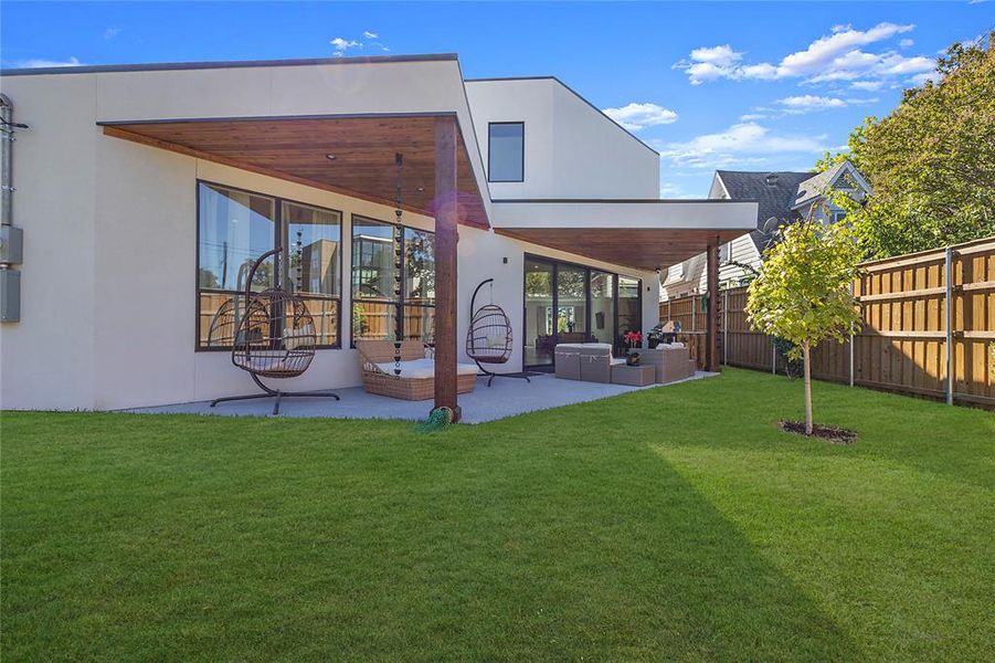 Rear view of property featuring a patio, an outdoor living space, and a lawn