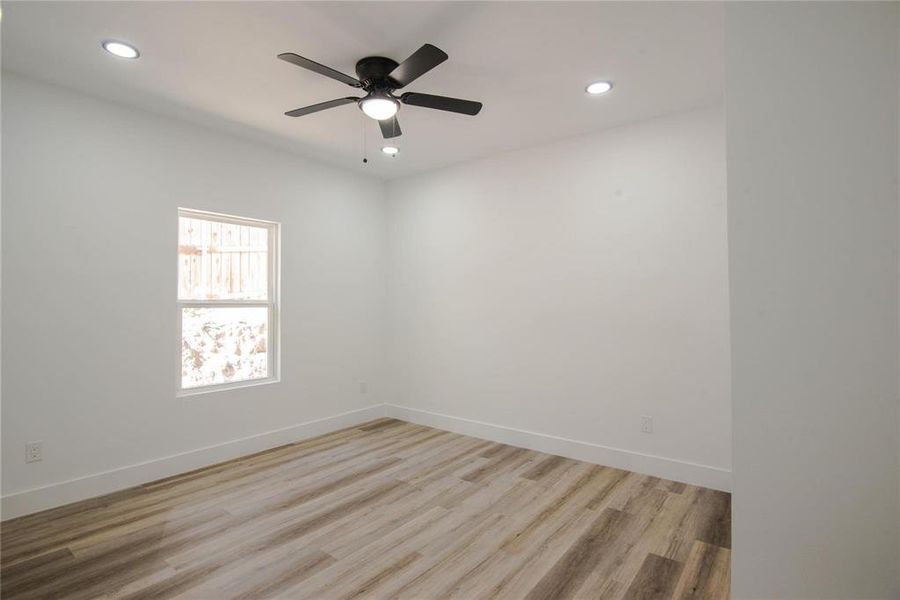 Empty room with ceiling fan and light hardwood / wood-style floors