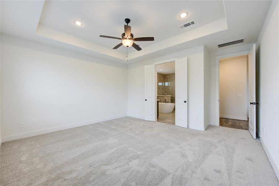 Spacious primary bedroom with recessed ceilings.