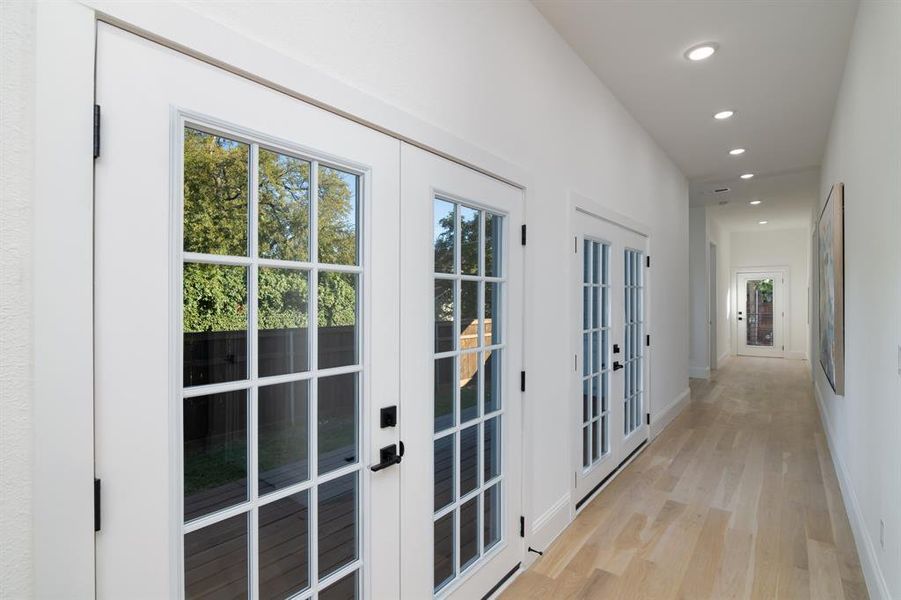 Corridor with french doors and light wood-type flooring