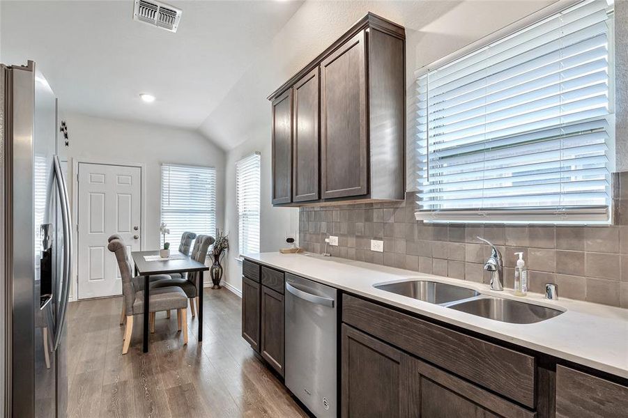 Kitchen featuring stainless steel appliances, a wealth of natural light, hardwood / wood-style flooring, and tasteful backsplash