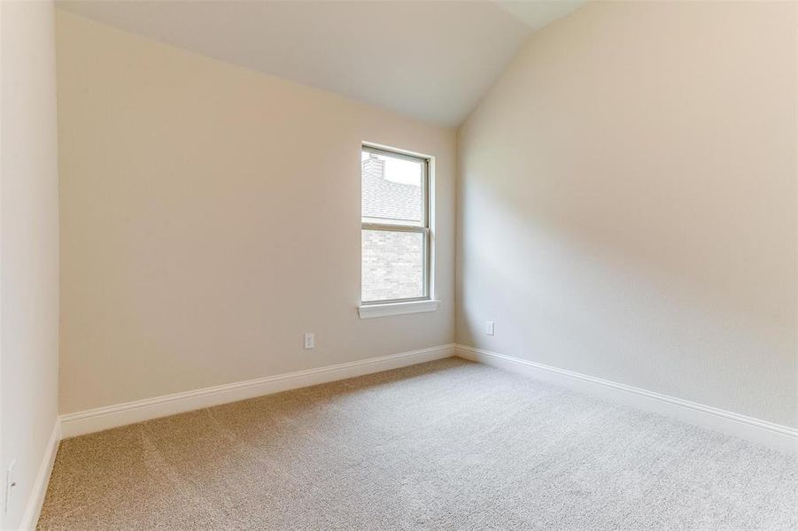 Empty room featuring vaulted ceiling and light colored carpet