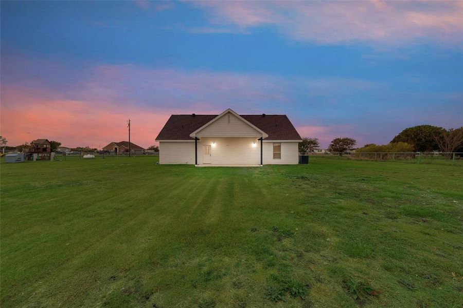 Back house at dusk with a lawn