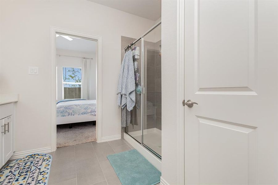 Bathroom featuring tile patterned flooring, a shower with door, and vanity