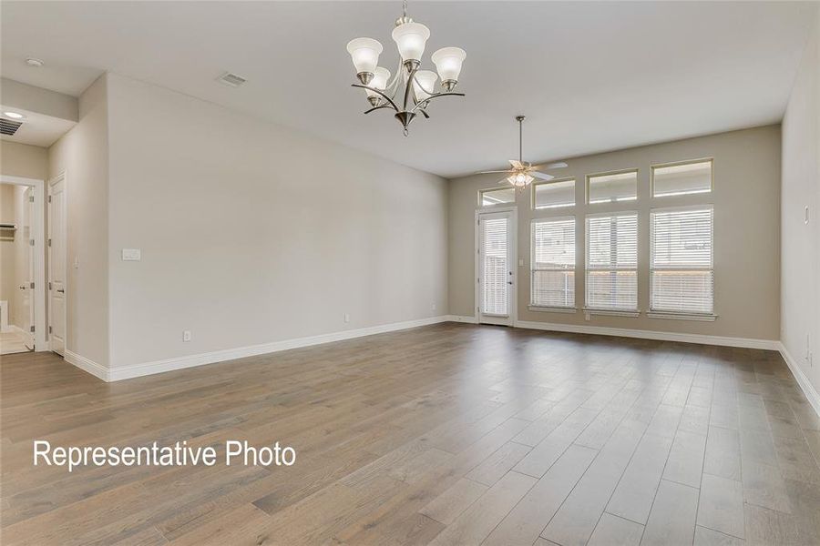 Spare room featuring ceiling fan with notable chandelier and hardwood / wood-style floors