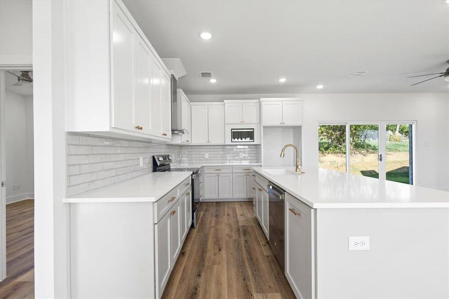 Kitchen with a center island with sink, white cabinetry, and stainless steel appliances