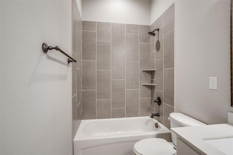 Full bathroom with vanity, tiled shower / bath combo, and toilet