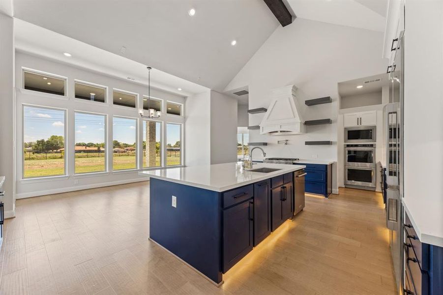 Kitchen featuring a kitchen island with sink, white cabinetry, sink, and blue cabinetry