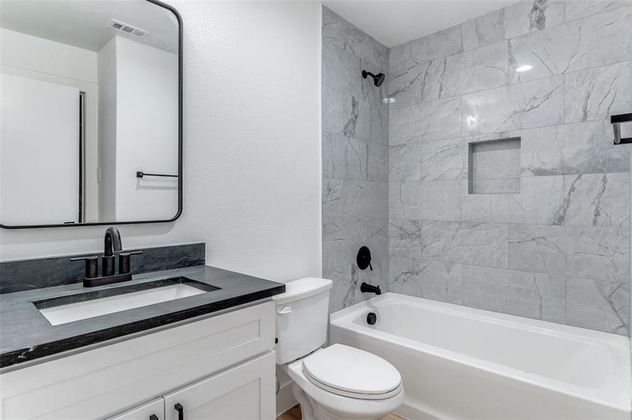 Full bathroom featuring tiled shower / bath combo, vanity, and toilet