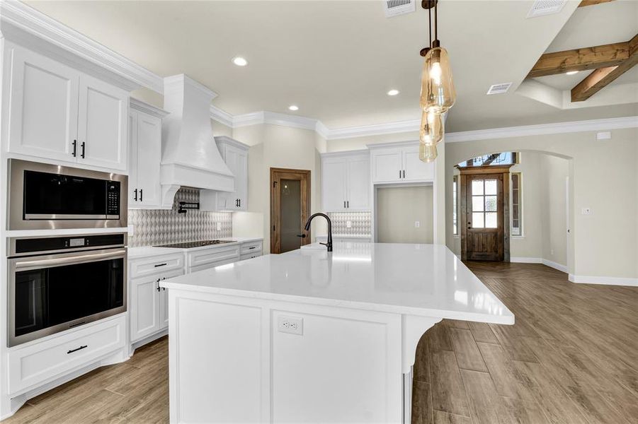 Kitchen with a kitchen island with sink, appliances with stainless steel finishes, light hardwood / wood-style flooring, and white cabinets