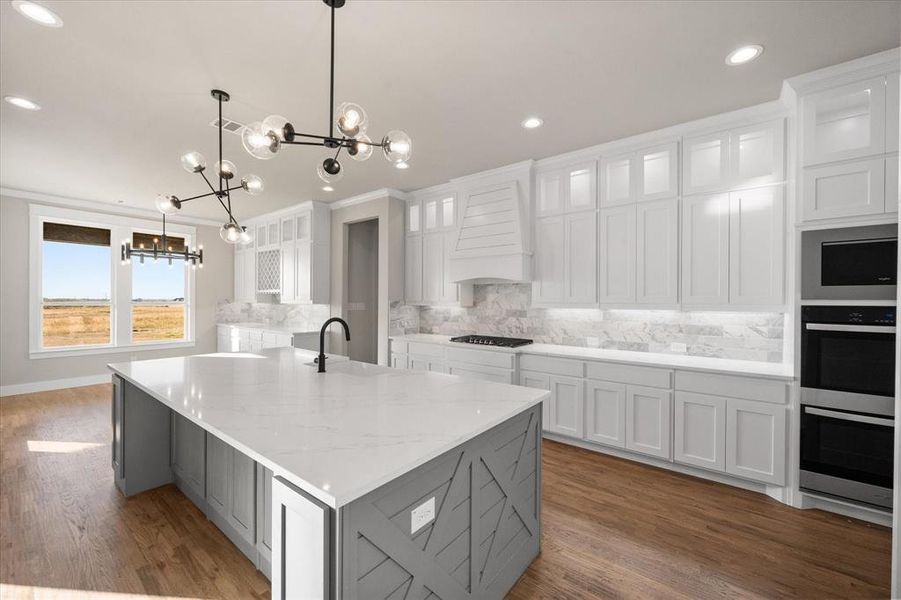 Kitchen featuring gas cooktop, a large island, a chandelier, white cabinets, and tasteful backsplash