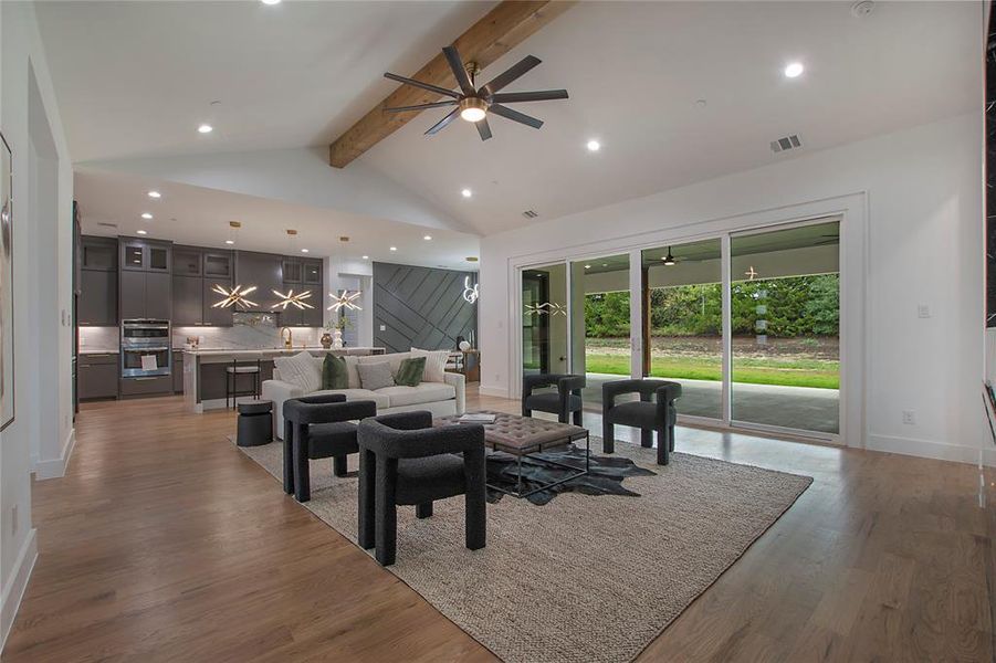 Living room with wood-type flooring, beam ceiling, and ceiling fan